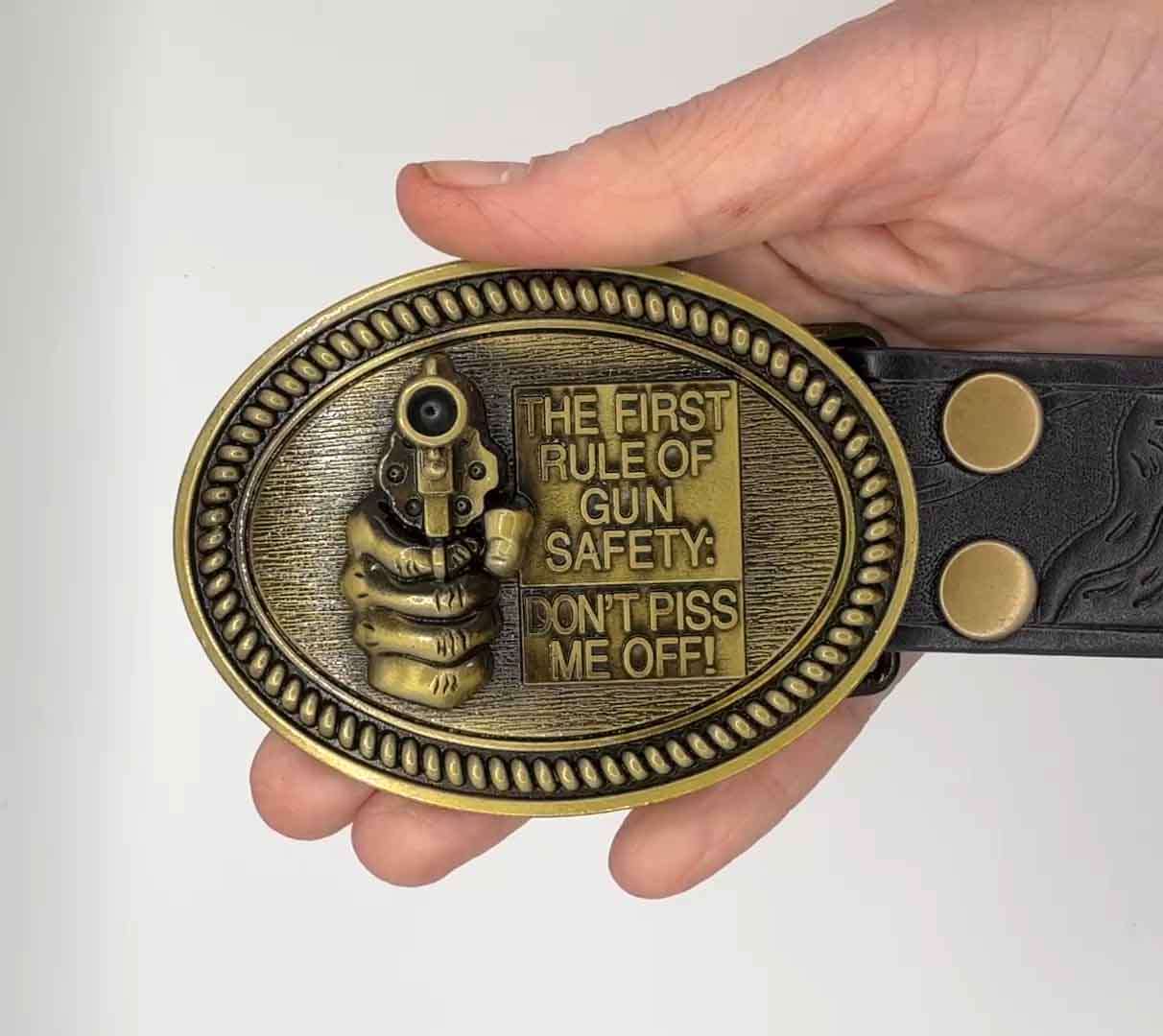 Antique gold gun safety belt buckle with raised revolver and bold safety message